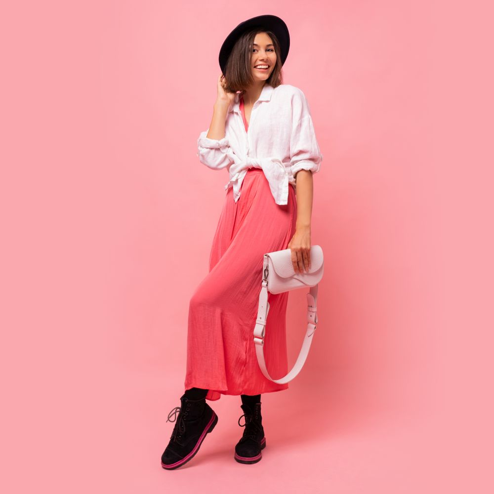Fashion studio photo of lovely brunette woman in  spring outfit posing in studio.  Holding white bag. Full lenght.