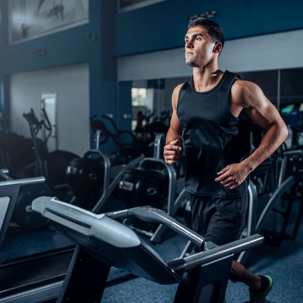 Male athlete workout on running exercise machine. Active sport training in gym