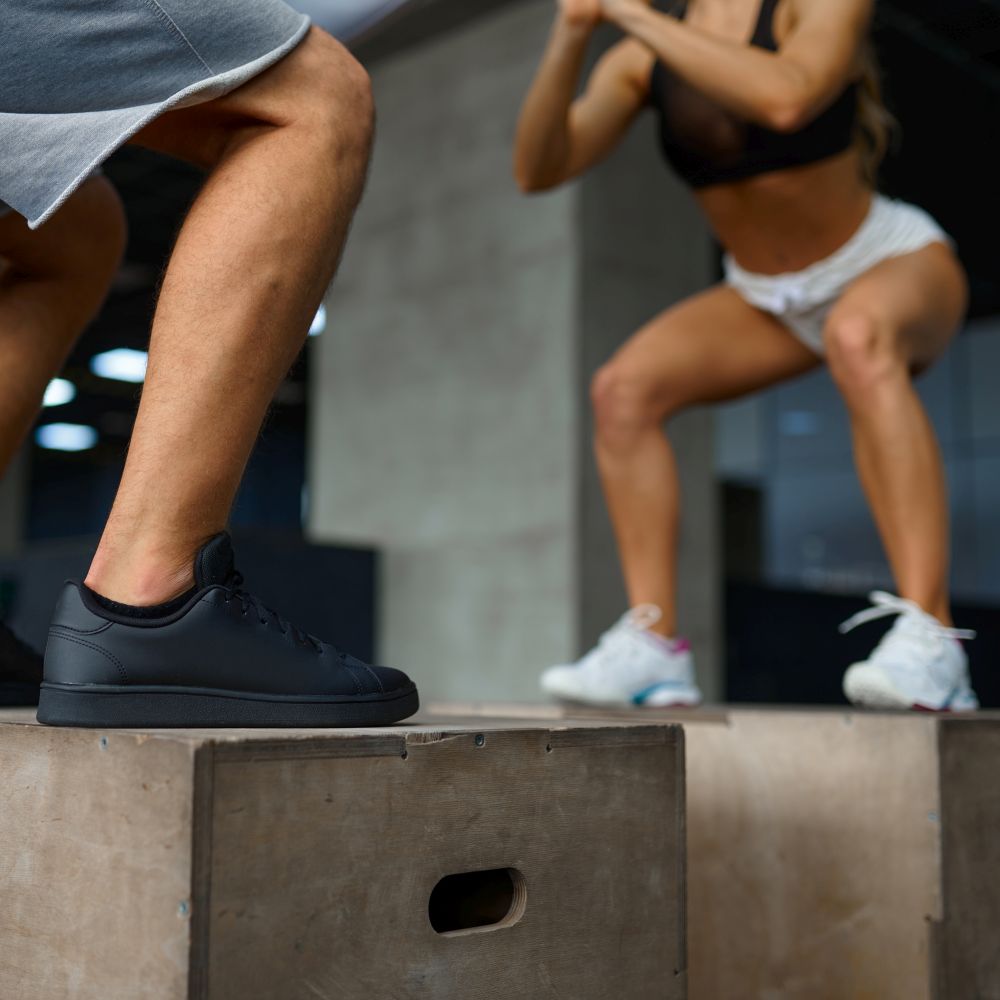 Slim couple doing balance exercise on cubes in gym. Man and woman in sport club, active healthy lifestyle, physical wellness